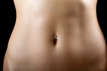 Image showing a sexy tummy of the young woman. Isolated on black