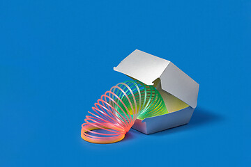 Image showing Flexible rainbow spring in a silver food container.