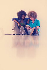 Image showing multiethnic couple sitting on the floor with a laptop and tablet