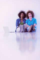 Image showing multiethnic couple sitting on the floor with a laptop and tablet