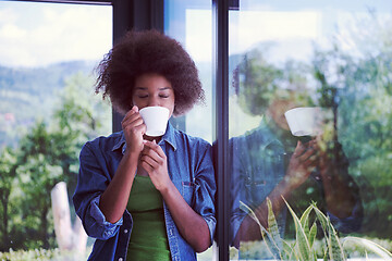 Image showing African American woman drinking coffee looking out the window