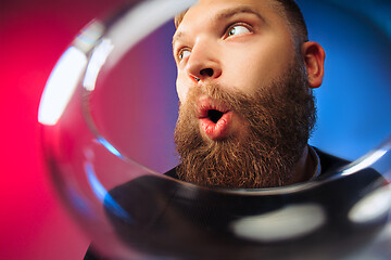 Image showing The surprised young man posing with glass of wine.