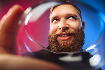 Image showing The surprised young man posing with glass of wine.