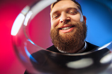 Image showing The surprised young man posing with glass of wine.