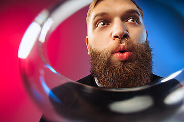 Image showing The surprised young man posing with glass of wine.