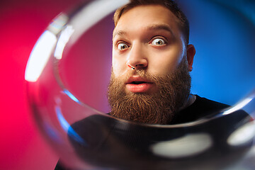 Image showing The surprised young man posing with glass of wine.