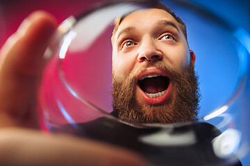 Image showing The surprised young man posing with glass of wine.