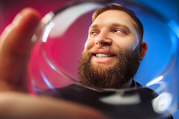 Image showing The surprised young man posing with glass of wine.