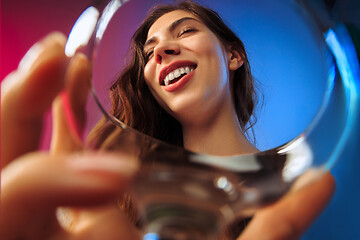 Image showing The surprised young woman in party clothes posing with glass of wine.