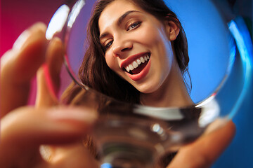 Image showing The surprised young woman in party clothes posing with glass of wine.