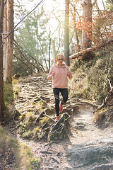 Image showing Active sporty woman listening to the music while running in autumn fall forest. Female runner training outdoor. Healthy lifestyle image of young caucasian woman jogging outside