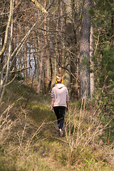 Image showing Rear view of active sporty woman listening to the music while running in autumn fall forest. Female runner training outdoor. Healthy lifestyle image of young caucasian woman jogging outside