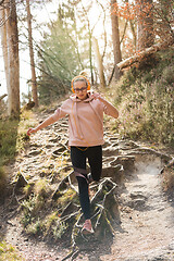 Image showing Active sporty woman running in autumn fall forest jumping over the roots on the path. Healthy lifestyle image of young active caucasian woman jogging outside in nature