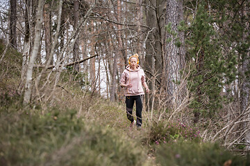 Image showing Active sporty woman listening to the music while running in autumn fall forest. Female runner training outdoor. Healthy lifestyle image of young caucasian woman jogging outside