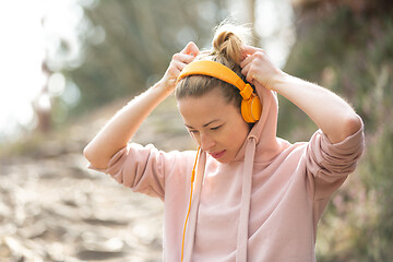 Image showing Portrait of beautiful sports woman with hoodie and headphones during outdoors training session.