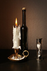 Image showing Sandglass, candlestick and black bottle 