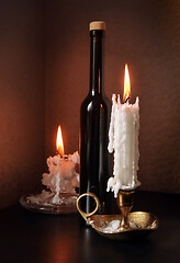 Image showing Two candlesticks and black bottle