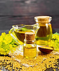 Image showing Oil mustard in two jars and gravy boat on dark board