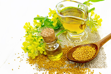 Image showing Oil mustard in jars and gravy boat on light board