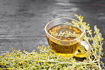 Image showing Tea of gray wormwood in glass cup on board