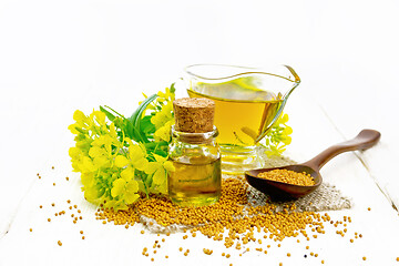 Image showing Oil mustard in jars and gravy boat on light wooden board