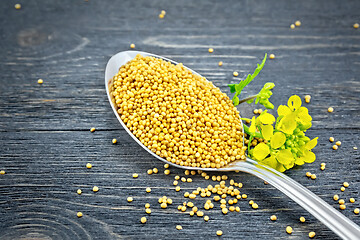 Image showing Mustard seeds in metal spoon with flower on board