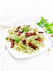 Image showing Farfalle with pesto and bacon in plate on table