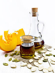 Image showing Oil pumpkin in jar and carafe on board