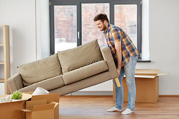 Image showing happy man moving sofa at new home