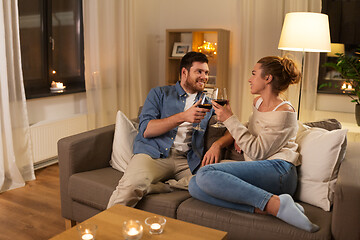 Image showing happy couple drinking red wine at home in evening