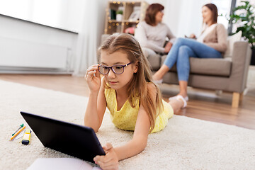 Image showing girl with tablet computer lying on floor at home