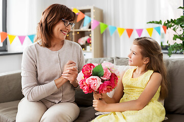 Image showing granddaughter giving grandmother flowers at home