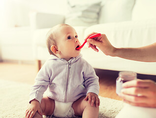 Image showing mother with spoon feeding little baby at home