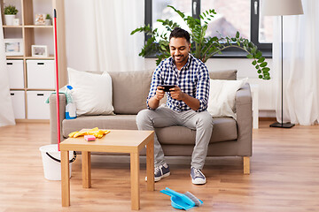 Image showing man playing game on smartphone after cleaning home