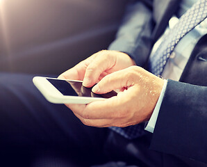 Image showing senior businessman texting on smartphone in car