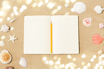Image showing notebook with pencil and seashells on beach sand