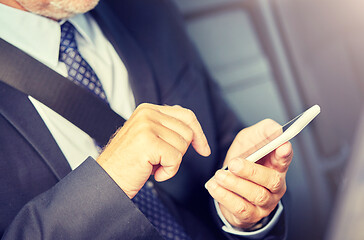 Image showing senior businessman texting on smartphone in car