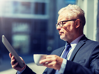 Image showing senior businessman with tablet pc drinking coffee