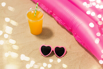 Image showing sunglasses, juice and pool mattress on beach sand