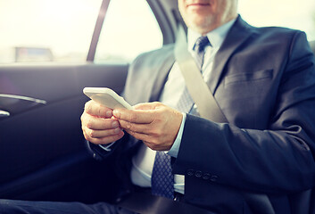 Image showing senior businessman texting on smartphone in car