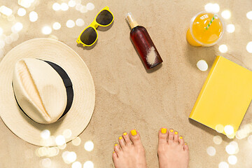 Image showing feet, hat, shades, sunscreen and juice on beach