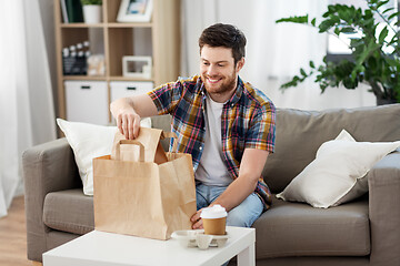 Image showing smiling man unpacking takeaway food at home