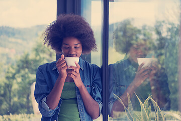 Image showing African American woman drinking coffee looking out the window