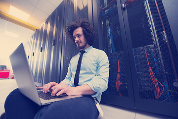 Image showing engineer working on a laptop in server room