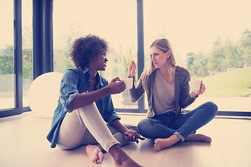 Image showing multiethnic women sit on the floor and drinking coffee