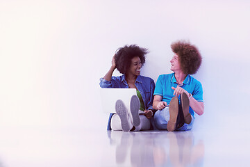 Image showing multiethnic couple sitting on the floor with a laptop and tablet