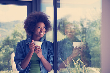 Image showing African American woman drinking coffee looking out the window