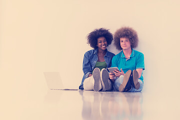 Image showing multiethnic couple sitting on the floor with a laptop and tablet