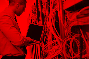 Image showing businessman with laptop in network server room