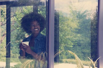 Image showing African American woman drinking coffee looking out the window